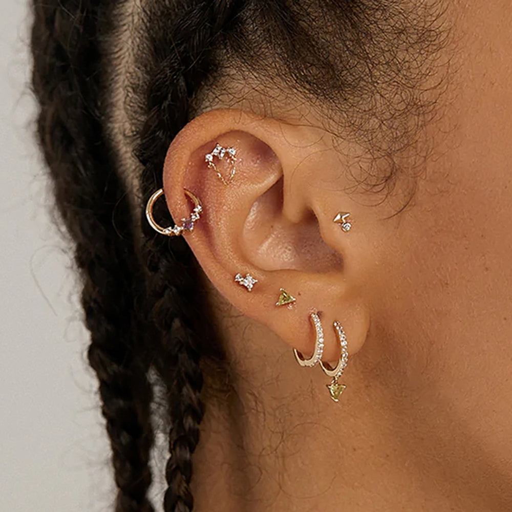 Woman wearing the earlobe piercing with white and violet zircons for the Helix