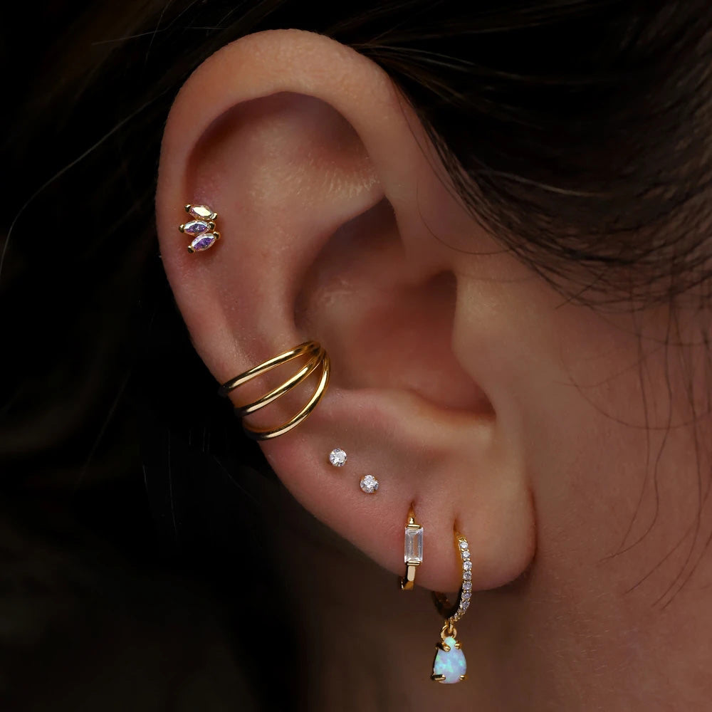 golden triple Earlobe hoop piercing worn by woman