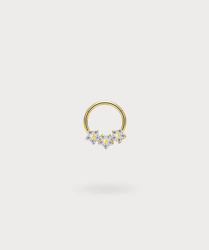 "Olaya Snug Piercing Ring in titanium with a golden finish, decorated with flowers and bright zircons."