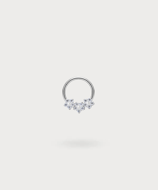 "Olaya Daith Piercing Ring in titanium, silver-toned, with three delicate flowers inset with zircons."