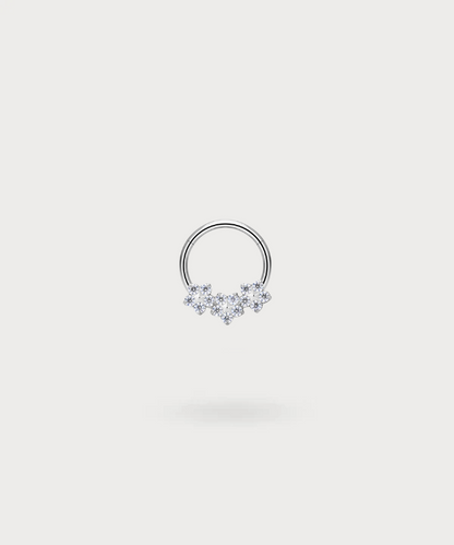 "Olaya Daith Piercing Ring in titanium, silver-toned, with three delicate flowers inset with zircons."