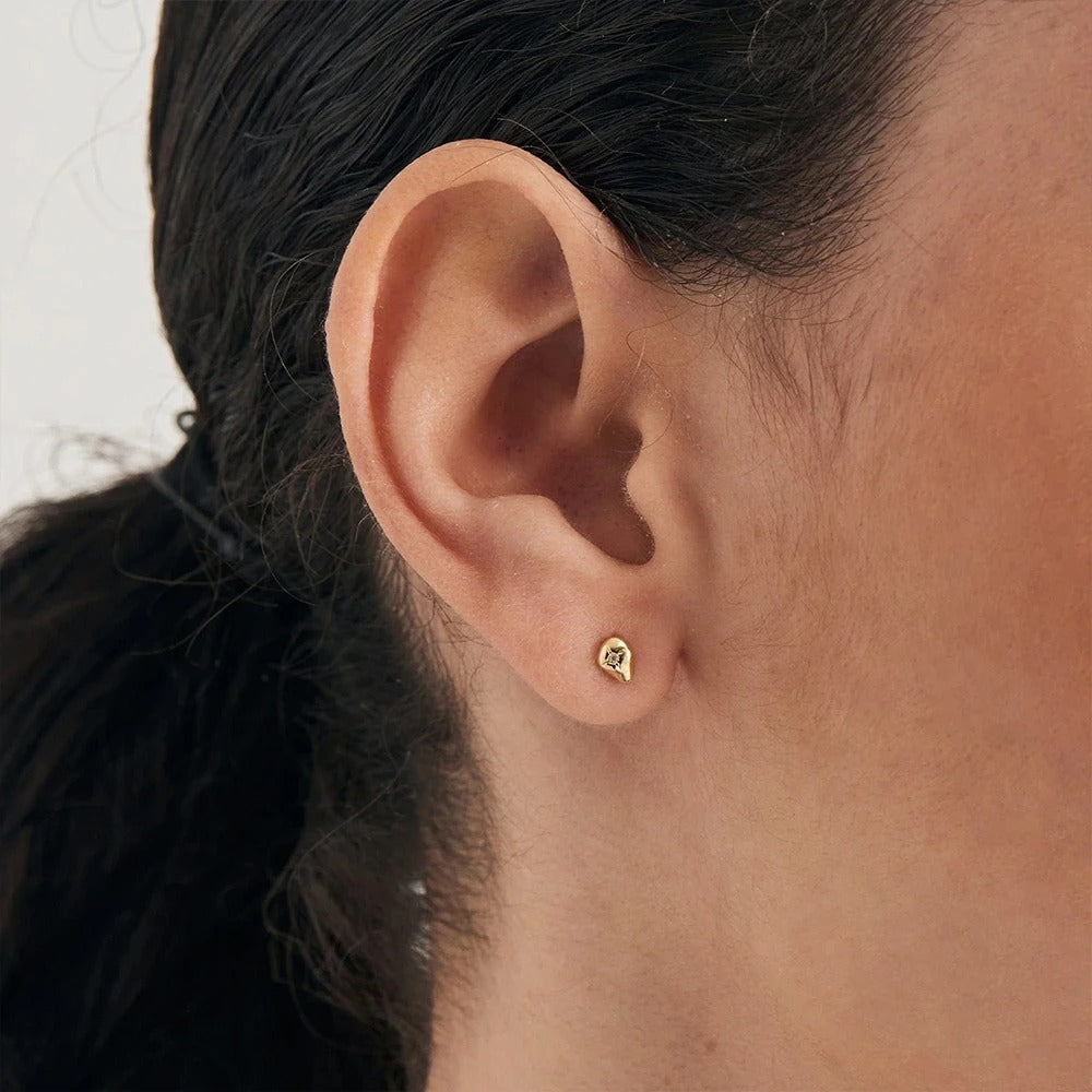 Helix piercing Montse, where the zircon sparkles at the heart of a golden/silver drop