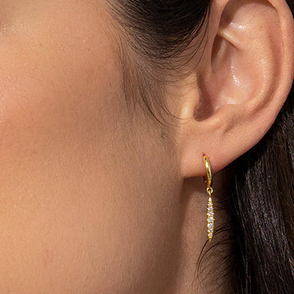 Gabriela's gold hoops, adorned with a shimmering zirconia pendant, encapsulate the essence of understated luxury and style.