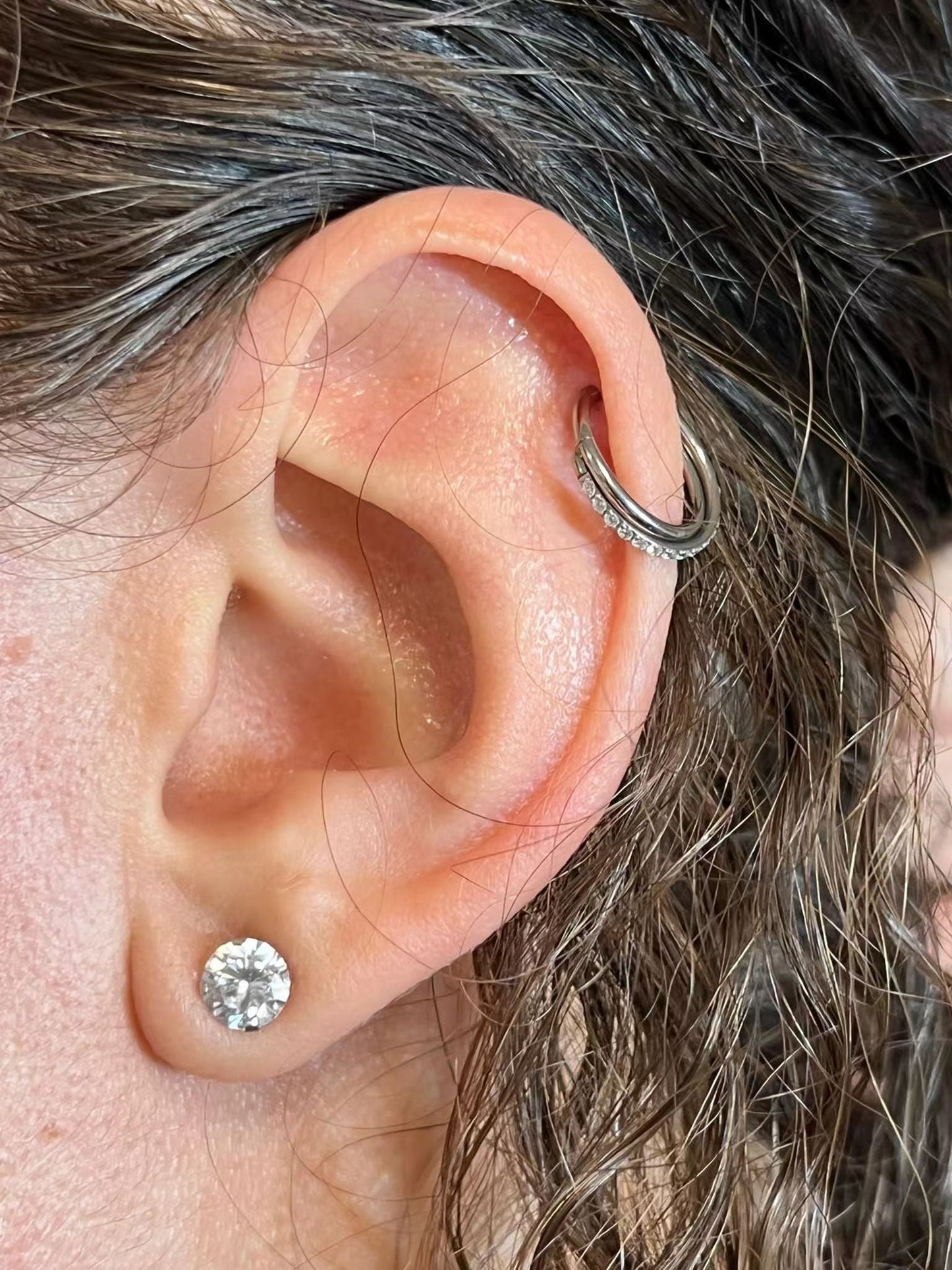 "Crossed Hoop Ear Piercing worn on a female ear."