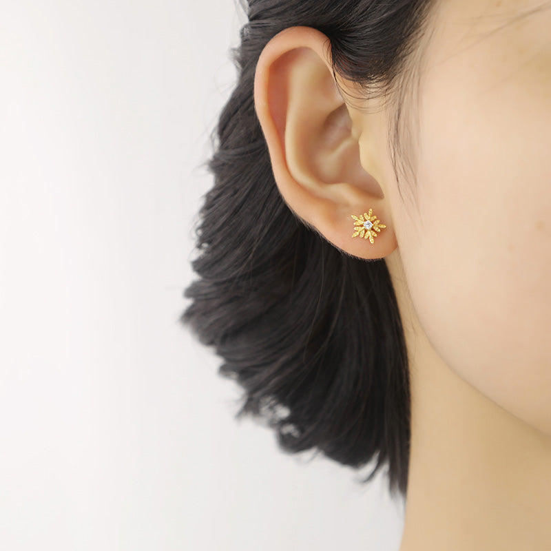 Woman wearing the Flora snowflake gold piercing at the earlobe - Helix piercing