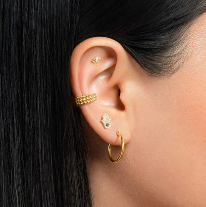 "Woman wearing the Helix Hand of Fatma Piercing in gold finish"