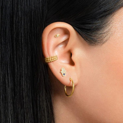 "Woman wearing the Forward Helix Hand of Fatma Piercing in gold finish"