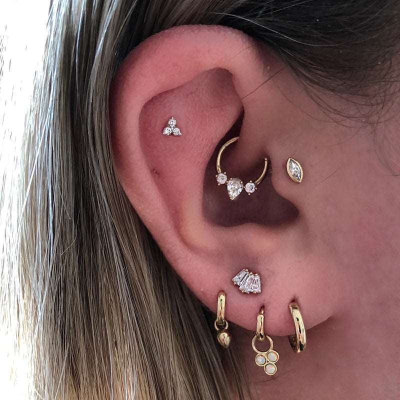 Daith Hoop and Zircon Piercing worn on an ear.